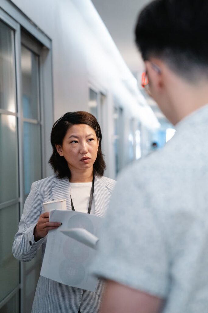 Two colleagues discussing work in an office hallway.